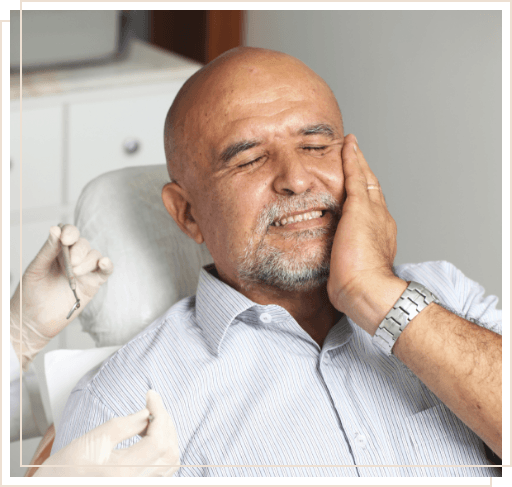 Man in dental chair holding side of face in pain
