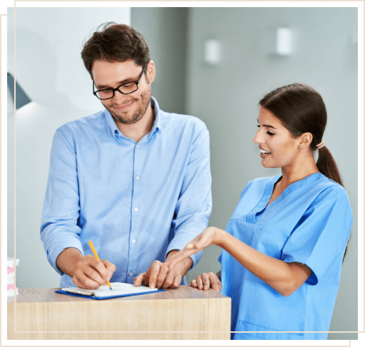 Dental team member showing a patient where to sign on clipboard