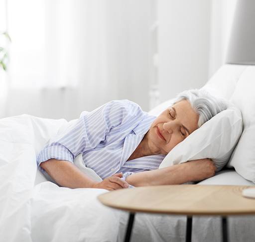 older woman resting in bed after dental implant procedure