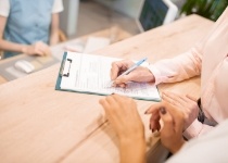 Person filling out form on clipboard