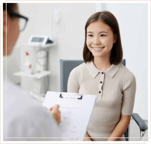 Woman smiling while her dentist fills out form on clipboard