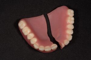 Two halves of broken dentures resting on a black background