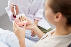 Patient looking at model of dental implant. 