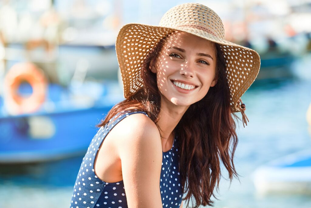 Woman in blue dress and straw hat at boat dock smiling